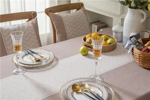 Close-up of beige woven tablecloth with herringbone pattern table runner and wavy fringe