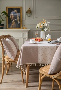 Detail of light brown jacquard tablecloth with white herringbone pattern and tassels