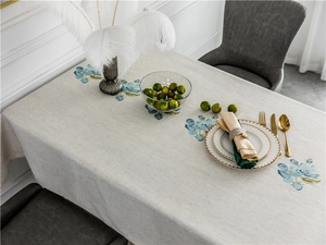 Close-up of elegant blue floral embroidery on linen-textured rectangular tablecloth