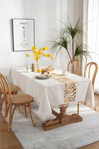 Close-up of oatmeal cotton linen tablecloth with zebra print pattern and white tassels