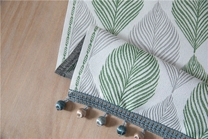 Detail of chenille table runner featuring jacquard leaf patterns and elegant bead tassels