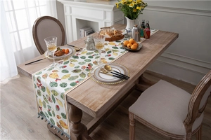 Detail of chenille table runner featuring leaf patterns and colorful pom-pom fringe