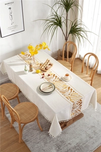 Close-up of beige cotton linen tablecloth featuring tiger patterns and fringe tassels