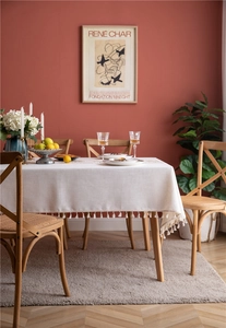 Close-up of beige linen tablecloth with white tassels in a vintage dining room setup