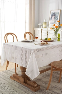 Detailed view of white openwork lace tablecloth with elegant vertical stripes and lace edges