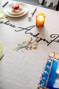 Detailed embroidery of floral wheat patterns and text on linen rectangular tablecloth