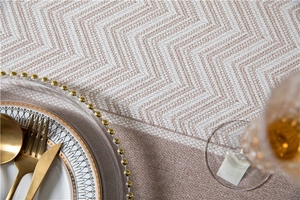 Detailed view of woven tablecloth featuring a beige and brown chevron pattern with gold cutlery