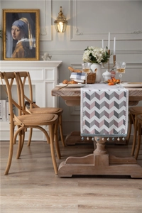 Close-up of chenille table runner with pink chevron pattern and white tassel trim