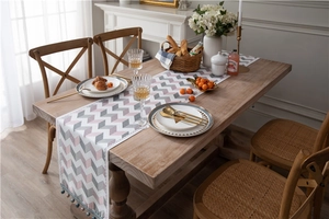 Detail of pink and grey zigzag jacquard chenille table runner with fringe on dark wood