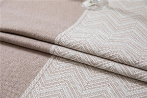 Macro detail of beige woven tablecloth featuring wavy jacquard patterns and textured fringe