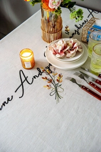 Close-up of elegant floral and cursive embroidery on a beige linen tablecloth
