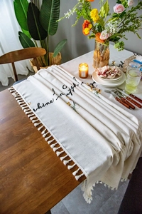Close-up of linen table runner with floral embroidery and elegant white tassels