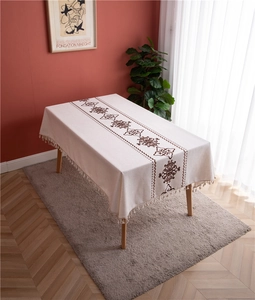 Detail of rectangular tablecloth featuring retro floral patterns and tassel fringe trim