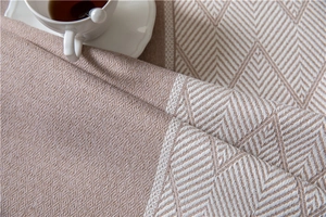 Macro detail of geometric jacquard tablecloth with textured weave and soft pink hues