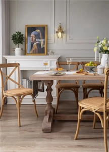 Close-up of a vintage solid wood dining table showing natural grain and a woven rattan chair