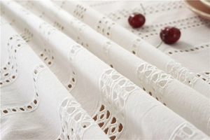Detailed macro view of white cotton lace tablecloth with floral hollow embroidery