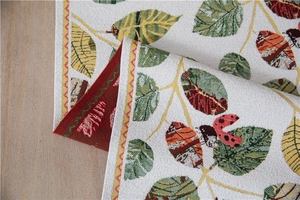 Detailed close-up of chenille table runner featuring leaf patterns and a ladybug icon