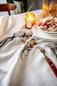 Close-up of beige linen tablecloth with floral and handmade letter embroidery
