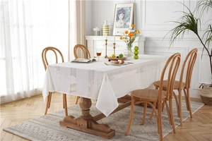 Close-up of white lace cotton tablecloth featuring hollow square embroidery on wood table