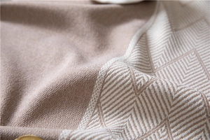 Detailed close-up of geometric jacquard patterns on beige thick woven fabric texture