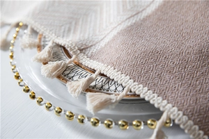 Close-up of beige jacquard tablecloth featuring wave fringe and woven diamond textures