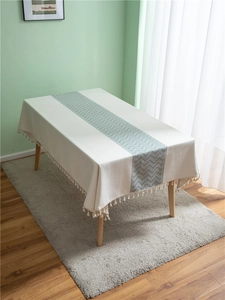 Detail of cream polyester jacquard tablecloth with green wave pattern and fringe