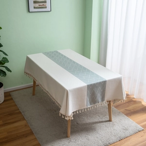 Detail of bohemian cream tablecloth with green geometric pattern and tassel fringe edges
