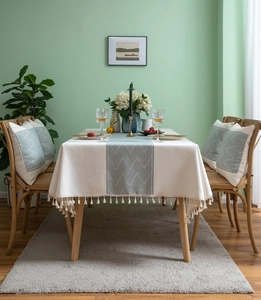 Detail of cream tablecloth with green wave pattern, tassel fringe and soft texture