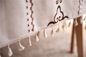 Detailed embroidery and fringe on beige cotton linen tablecloth with ethnic cloud patterns