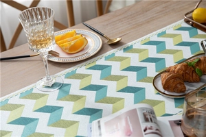 Close-up of green and yellow zigzag jacquard chenille table runner with fringe detail