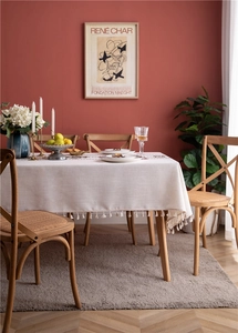 Detail of cream tablecloth with geometric embroidery, fringe edges, and linen texture