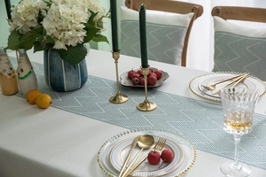 Detailed close-up of teal geometric jacquard table runner with fringe and woven texture