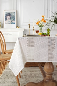 Detail of white cotton lace tablecloth with floral hollow patterns and grid textures