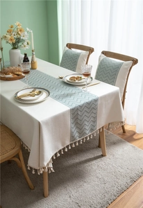 Close-up of cream table cloth with green wave jacquard and elegant woven fringe