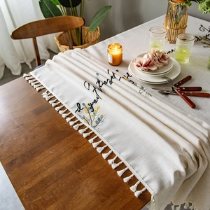 Linen tablecloth with floral embroidery and white tassels in a cozy dining setting