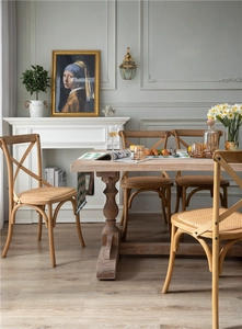 Detail of cross-back wooden dining chairs with woven rattan seats and roman column table