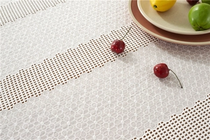 Close-up of white floral lace tablecloth with intricate hollow embroidery on wood