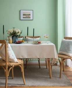 Detailed view of woven geometric ripple texture and fine beige fringe on a cream tablecloth
