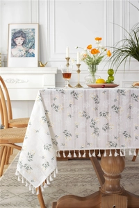 Detail view of cotton tablecloth featuring lilac floral patterns and white fringe tassels