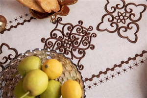 Close-up of beige linen tablecloth featuring brown cloud floral embroidery details