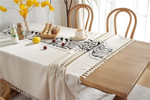 Detail of embroidered zebra pattern and elegant white tassels on a cream linen tablecloth