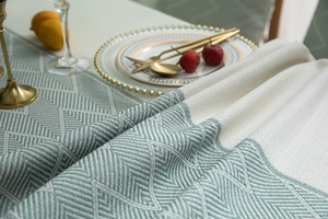 Detail of sage green chevron jacquard tablecloth with premium woven texture and fringe