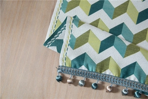 Detailed view of jacquard chevron chenille fabric with green silk tassels on wood table