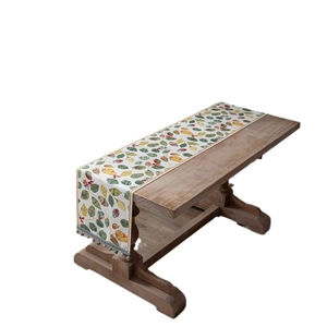 Chenille table runner with autumn leaf pattern and decorative tassels on a wooden table