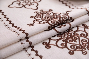 Close-up of elegant floral embroidery on beige linen tablecloth with premium texture