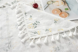 Detail of floral embroidery and white tassels on a rectangular cotton tablecloth