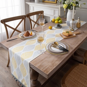 Modern chenille table runner with yellow leaf patterns and colorful tassel accents