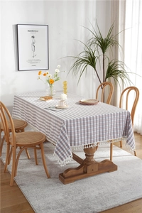 Detail of pink and grey plaid tablecloth featuring delicate white fringe tassels