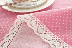 Close-up of pink polka dot tablecloth with white lace trim and cotton linen texture