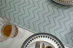 Detail of Morandi green wavy pattern jacquard tablecloth with fringe edges for dining decor